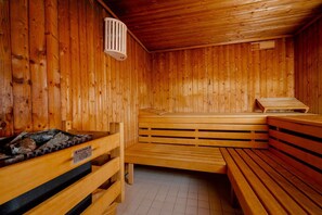 A wooden sauna with benches and a bench with a heating element. - Sünhair with a pool and sauna—A combined living and sleeping space with   (Sylt)