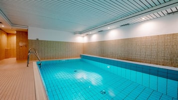 Ein Schwimmbecken mit gefliesten Wänden und einer Metallleiter.
