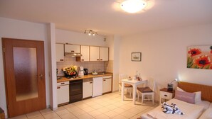Ein kleines Hotelzimmer mit Küchenzeile, Essbereich und Bett.