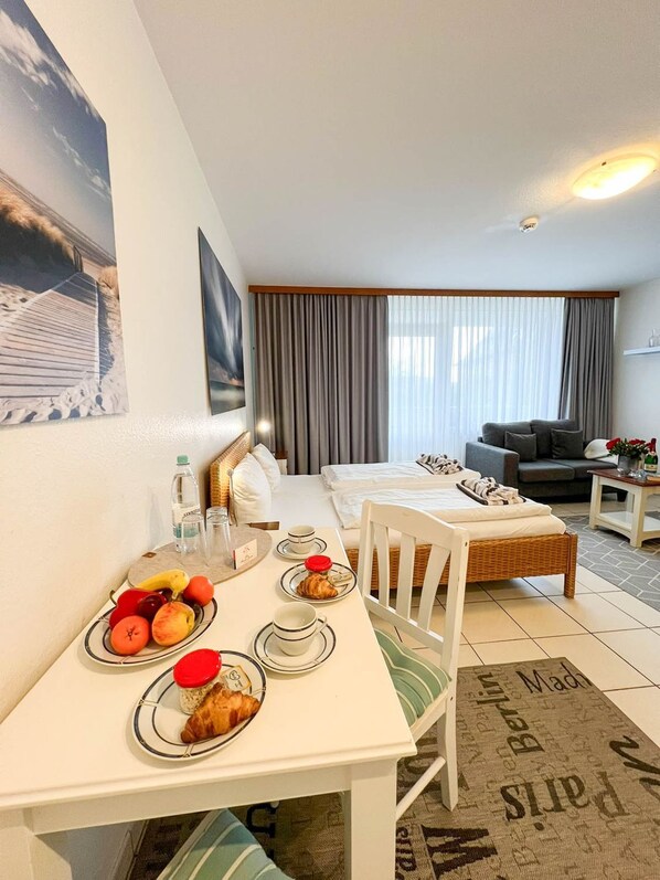 Una habitación de hotel con una mesa de comedor lista para el desayuno, un sofá y una cama.