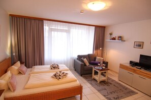 Ett hotellrum med en säng, en soffa, ett skrivbord och en tv.