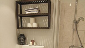 A compact bathroom with a toilet, a shower, and a shelf above the toilet. - Strönwai - Perfect for sunbathing or enjoying the vacation life of the Strandstraße (Sylt)