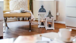 Una habitación acogedora con una cama de cabecera capitonada, un radiador blanco y dos faroles con velas.