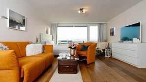 Una sala moderna con un sofá, un sillón y una mesa de centro con un jarrón.