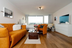 Ein modernes Wohnzimmer mit Sofa, Sessel und Couchtisch mit Vase.