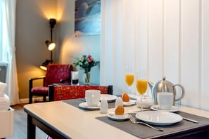 Une table mise pour le petit-déjeuner, avec des assiettes, des tasses, une théière et un vase rempli de fleurs.