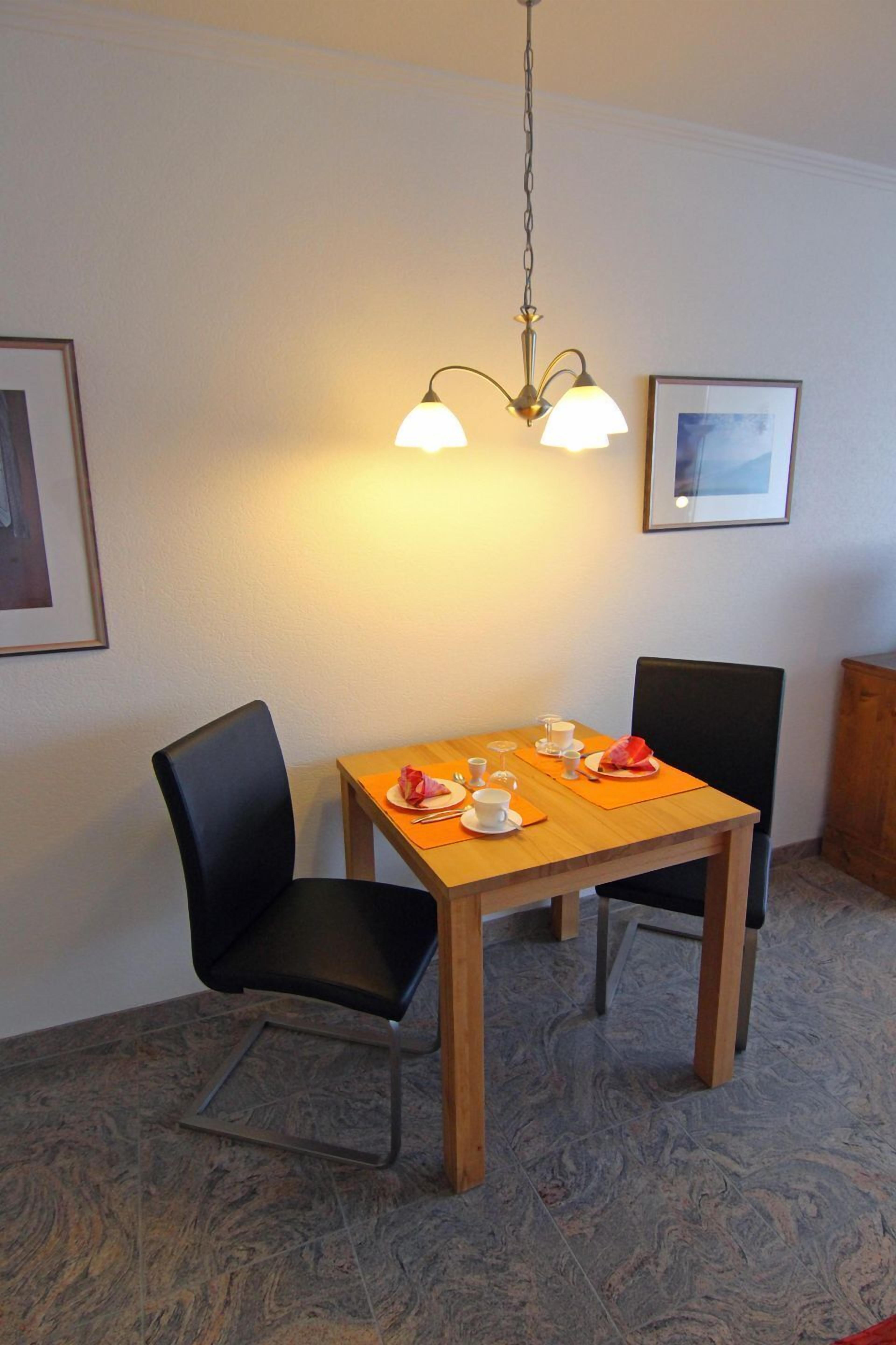 Ein Essbereich mit Holztisch, schwarzen Stühlen und einer hängenden Leuchte.