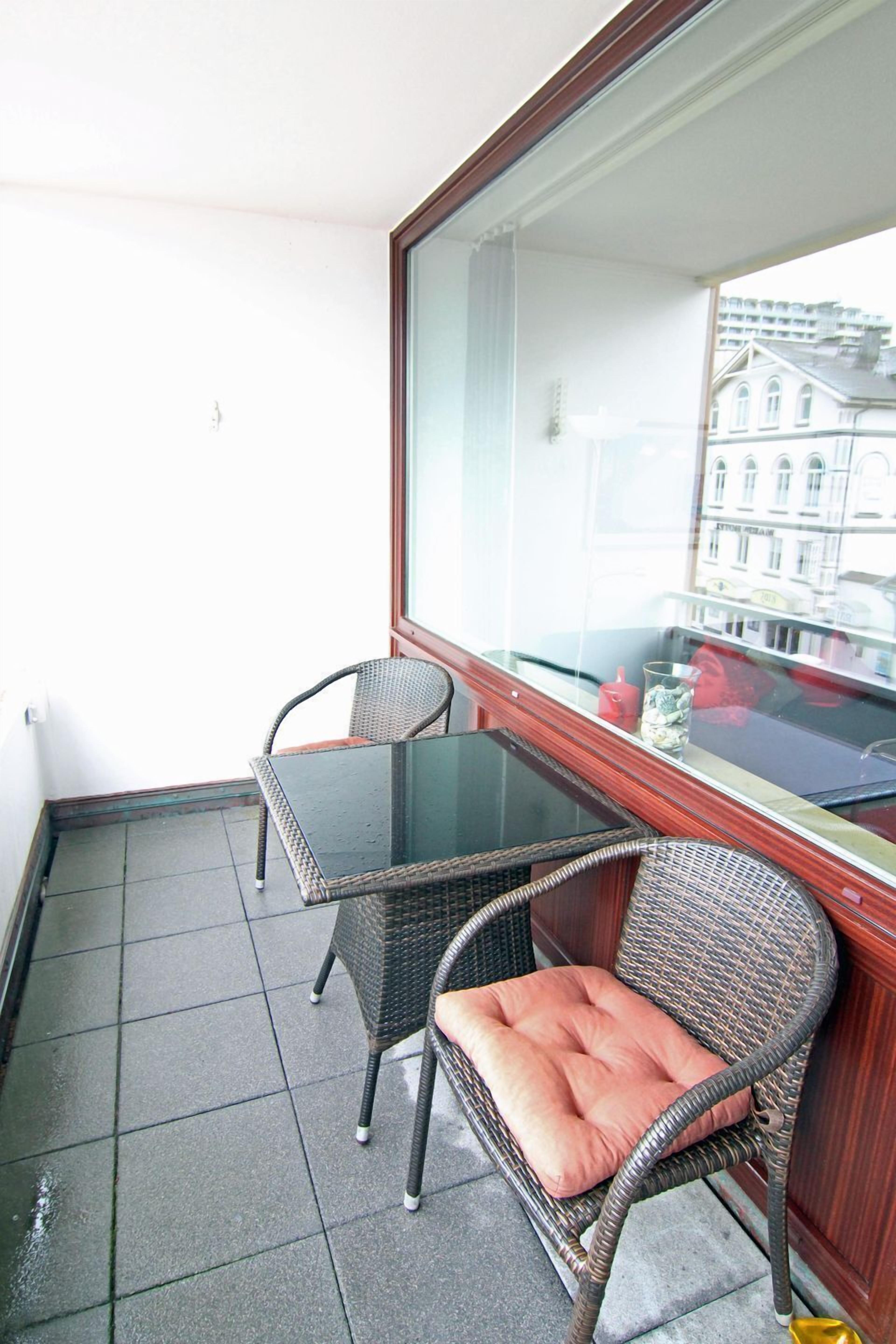 Ein Balkon mit zwei Korbstühlen und einem Glastisch.