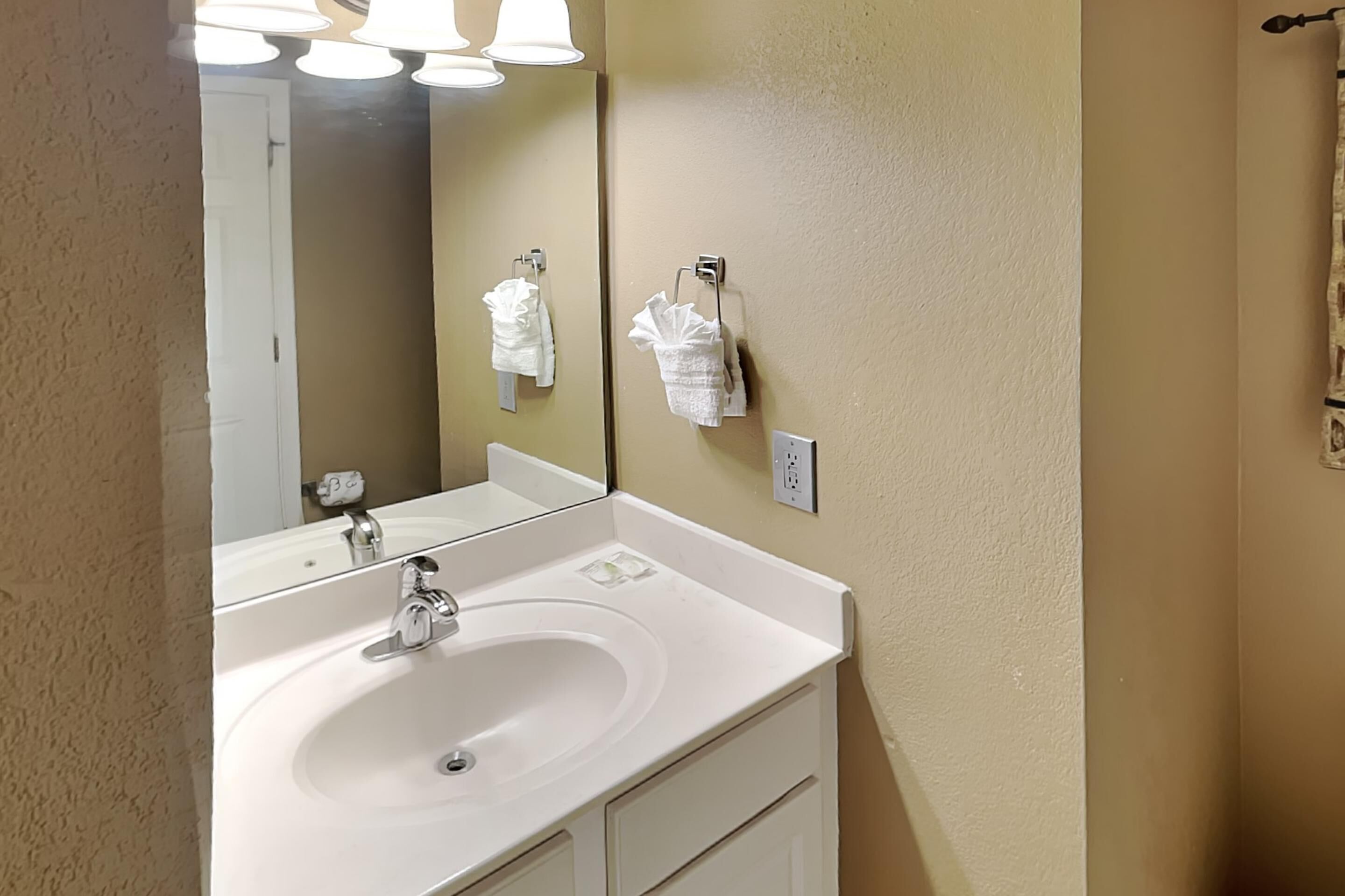 A bathroom with a white sink, a mirror, and two towel racks.