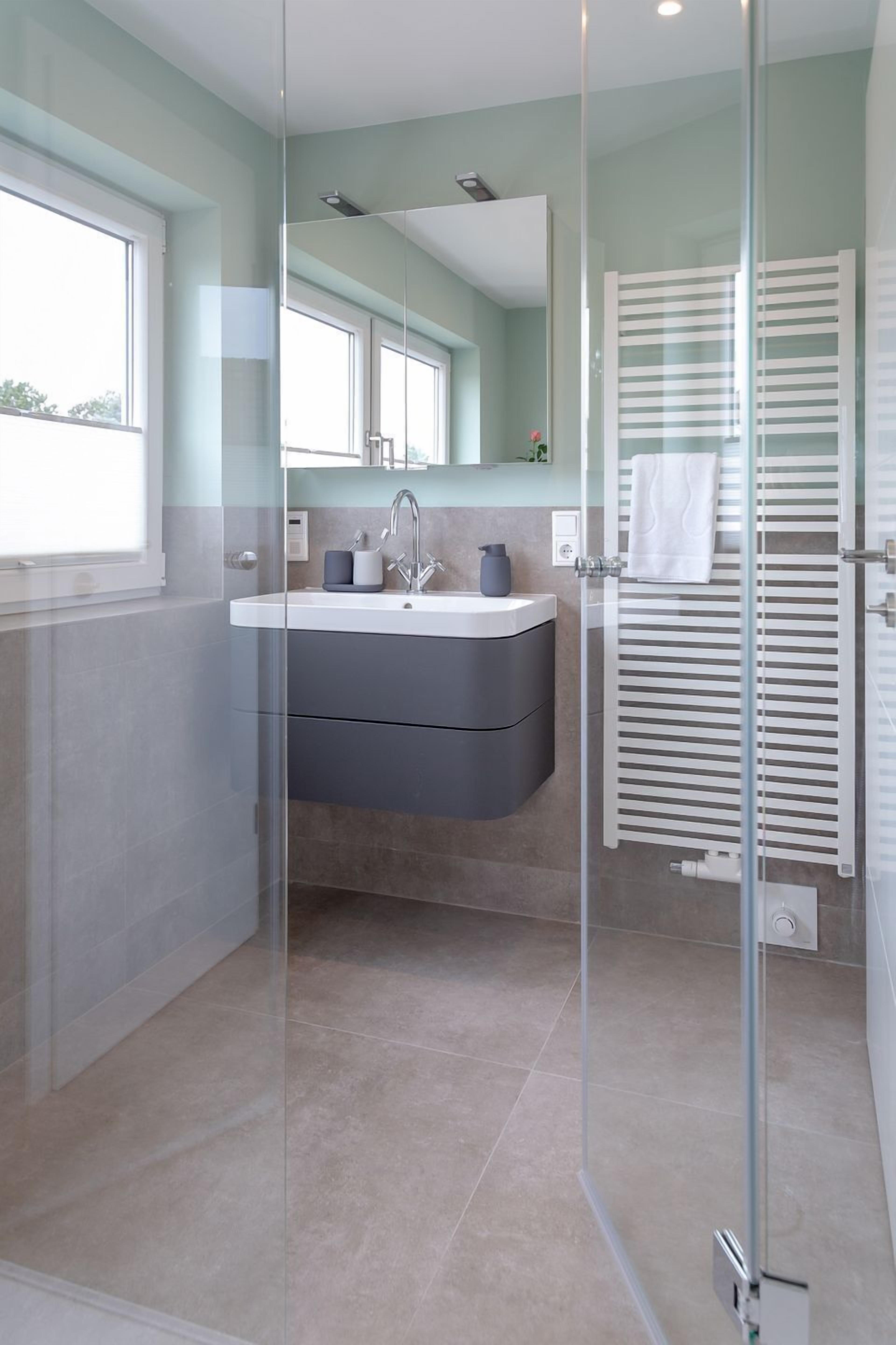 Een moderne badkamer met een douchecabine, een wastafelmeubel en een handdoekrek.
