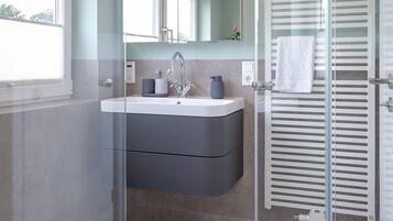 Een moderne badkamer met een douchecabine, een wastafelmeubel en een handdoekrek.