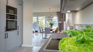 A modern kitchen with built-in appliances, a dining area with a table and chairs, and a large window providing natural light.