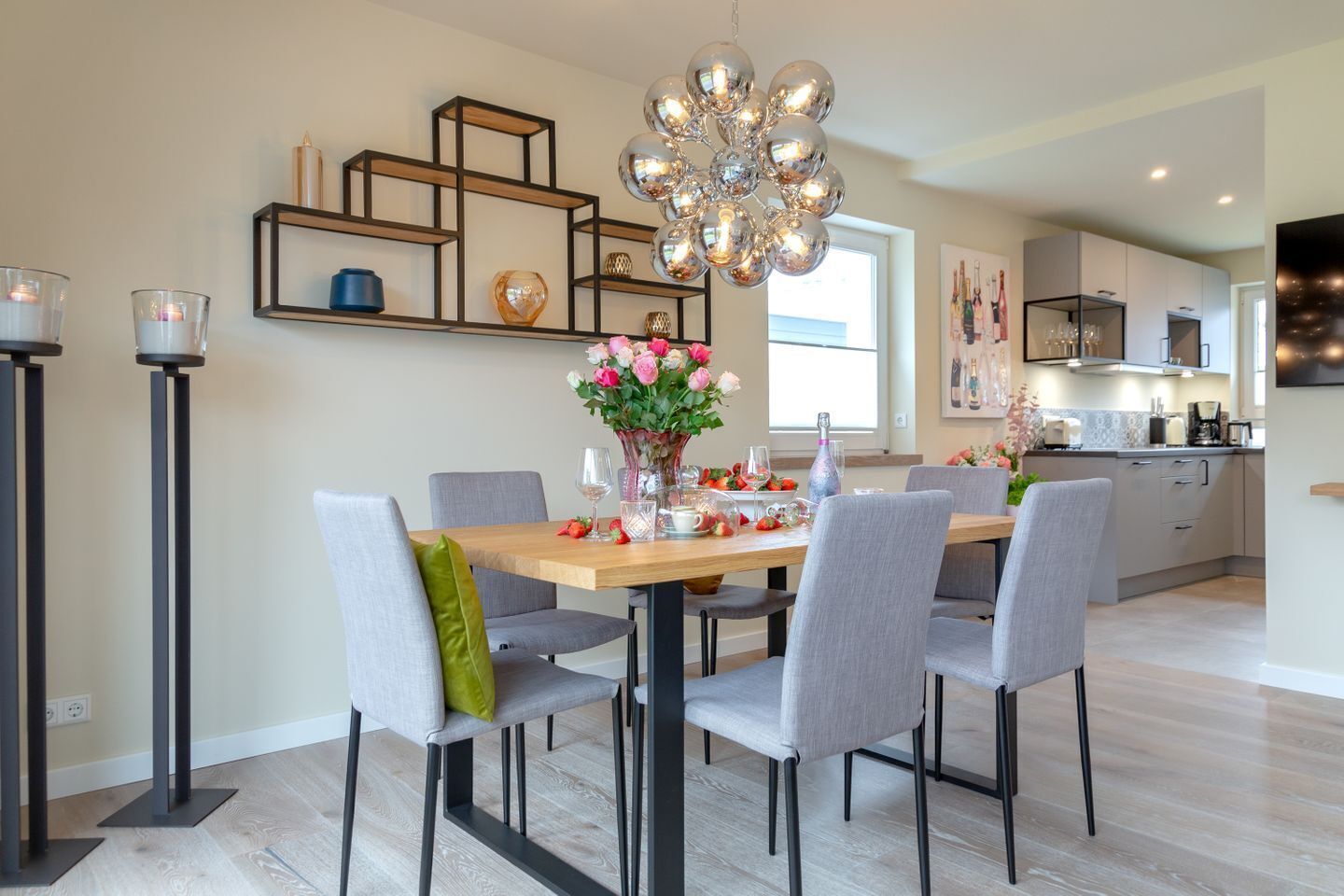 Un comedor moderno con una mesa de madera, sillas tapizadas en gris y una lámpara decorativa.