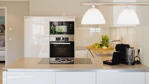 Een moderne keuken met een ingebouwde oven, een koffieapparaat en een eethoek met een tafel en stoelen.