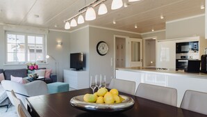 Een moderne keuken met een eettafel gedekt voor een maaltijd, een bank en een televisie in de woonkamer.