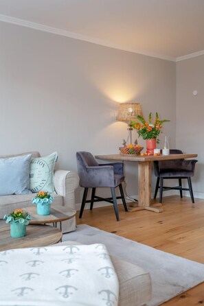 Ett modernt vardagsrum med en soffa, ett matbord med stolar, en lampa och dekorativa föremål.