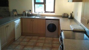 A compact kitchen with a washing machine, a sink, and a stove.