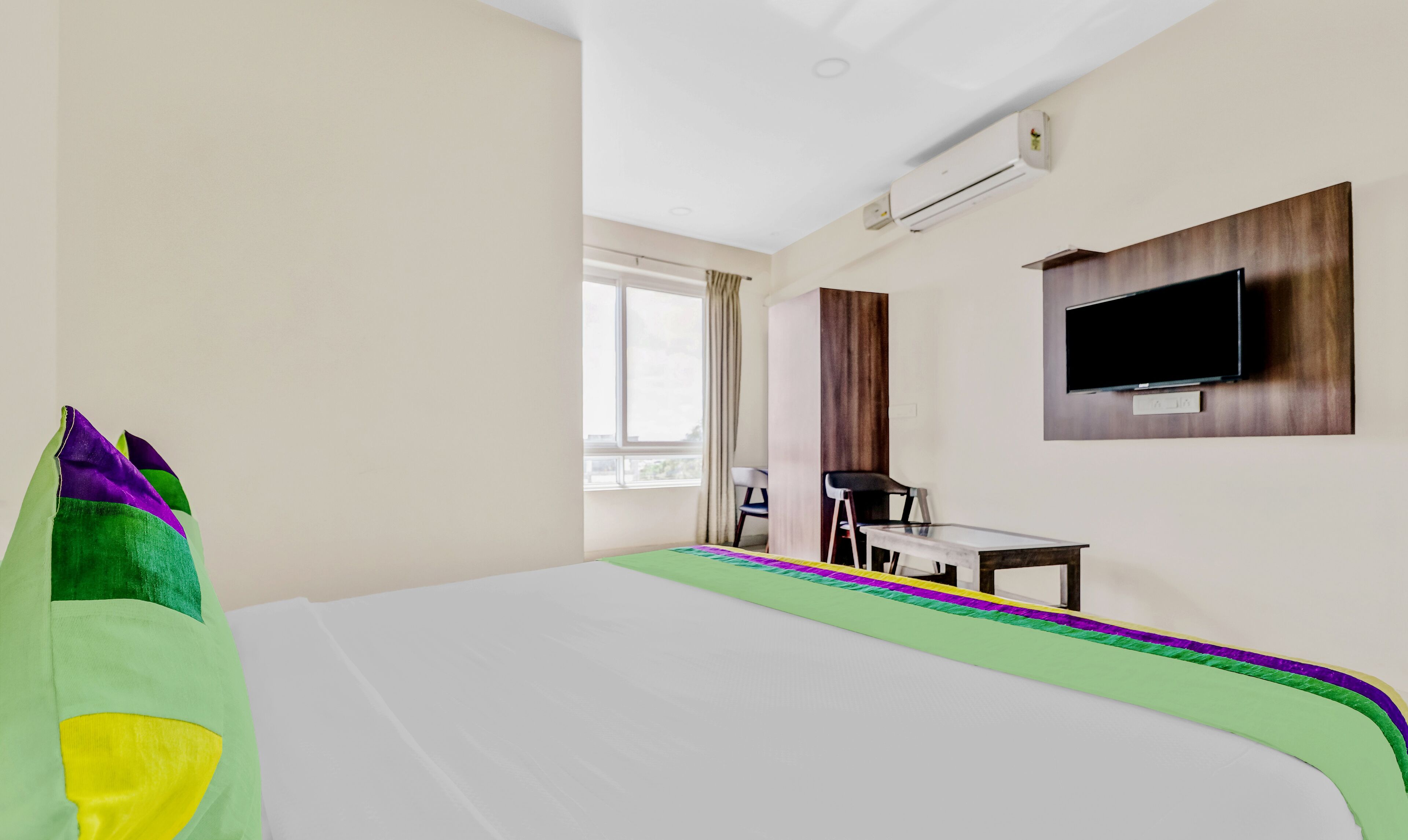 A hotel room with a bed, a desk, a chair, a TV, and a window.