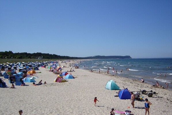 A beach with numerous tents and people enjoying the seaside.