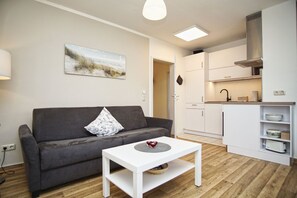 Ein modernes Wohnzimmer mit einem grauen Sofa, einem weißen Couchtisch und einem Bild mit einer Strandansicht.