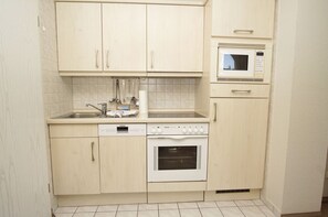 A compact kitchen with a dishwasher, oven, microwave, and a sink.