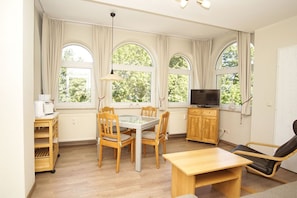 A room with a dining table, chairs, a television, and a sofa. - Close to the beach, with balcony - Villa Strandmuschel FeWo 07 - Villa Strandmuschel (Göhren)