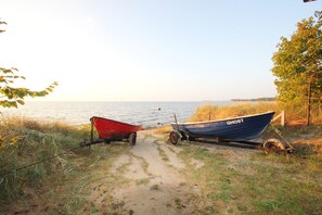 Deux bateaux, l’un rouge et l’autre bleu, étaient amarrés sur un chemin de terre, au bord de l’eau.