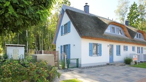 Ett traditionellt hus med ett halmtak, vita väggar och blåa fönsterluckor.