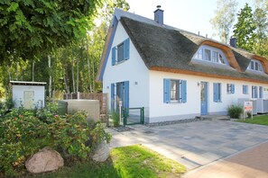 A traditional house with a thatched roof, white walls, and blue shutters. - Vacation home Stranddistel - close to the beach, thatched roof, with garden, sauna, dog-friendly (Glowe)