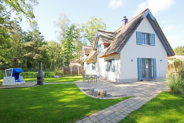 A house with a thatched roof, white walls, and blue shutters. - Vacation home Stranddistel - close to the beach, thatched roof, with garden, sauna, dog-friendly (Glowe)