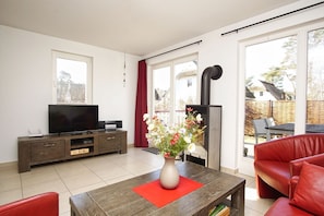 A modern living room with a TV, wooden cabinet, red sofa, and a fireplace.