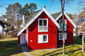 Ein rotes Haus mit zwei Stockwerken, weißem Zierdekor und einer kleinen Veranda.