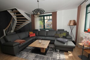 A modern living room with a sectional sofa, a wooden coffee table, a floor lamp, and a staircase.