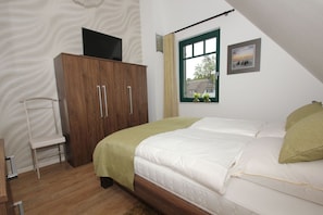 Une chambre à coucher comprenant un lit, une armoire, une fenêtre avec vue et une petite table avec une chaise.