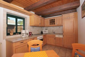 A kitchen with wooden cabinets, a microwave, a coffee maker, and a sink. - Beachfront House with Terrace and Garden - Ferienhaus Storchennest Haus L - (Wiek)