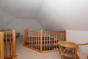 Ein Zimmer mit einer Holztreppe, einem grünen Sofa und einem Korbstuhl.