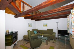 Ein Wohnzimmer mit einer Holztreppe, einem Sofa, einem Glastisch und einem Fernseher.