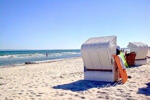 Beach chairs made of woven material on a sandy beach with the ocean in the background. - Beachfront House with Terrace and Garden - Ferienhaus Storchennest Haus L - (Wiek)