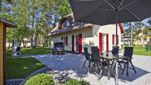 Ein Patio mit Gartenmöbeln und einem Gebäude mit einem Reetdach.
