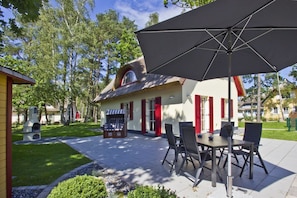 Un espace patio avec des sièges extérieurs et un bâtiment doté d’un toit de chaume.