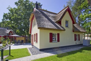 A traditional house with a steeply pitched roof, red shutters, and a well-maintained garden. - Haus Ostseesonne - close to the beach, quiet location, own sauna, beautiful garden - (Glowe)