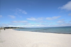A beach with a clear sky, calm sea, and a few people walking. - Haus Ostseesonne—close to the beach, quiet location, private sauna, beautiful garden— (Glowe)