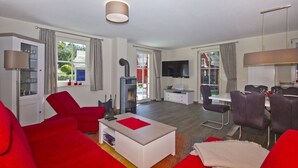 Ein modernes Wohnzimmer mit roten Sofas, einem weißen Couchtisch, einem Fernseher und einem Kamin.