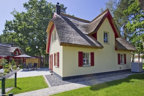 A traditional house with a steeply pitched roof, red shutters, and a well-maintained garden. - Haus Ostseesonne—close to the beach, quiet location, private sauna, beautiful garden— (Glowe)