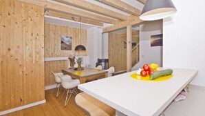 A modern kitchen with wooden accents, a dining area with white chairs, and a fruit bowl on the counter. - Vacation home Saga - close to the beach, modern house with own sauna, garden, terrace - (Wiek)