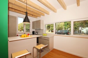 Eine moderne Küche mit Holzbalken, einem großen Fenster und einer Obstschale auf der Arbeitsfläche.