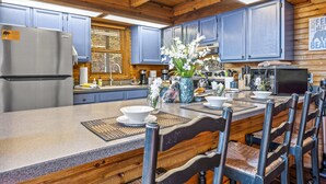 Una cocina con armarios de madera, un refrigerador y un comedor con sillas y una mesa.