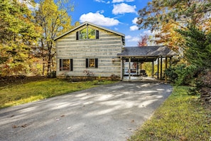 A rustic log cabin with a covered porch and a small adjacent structure. - Secluded Unobstructed Panoramic Mtn View w/ Dual Suites+Loft+ Game Room+Hot Tub (Gatlinburg)