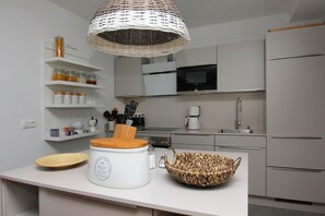 A modern kitchen with white cabinets, a microwave, a coffee maker, and a wicker bowl on the counter. - Freya Vacation Home - Cozy Swedish-style home near the beach with a view of the sea - (Wiek)