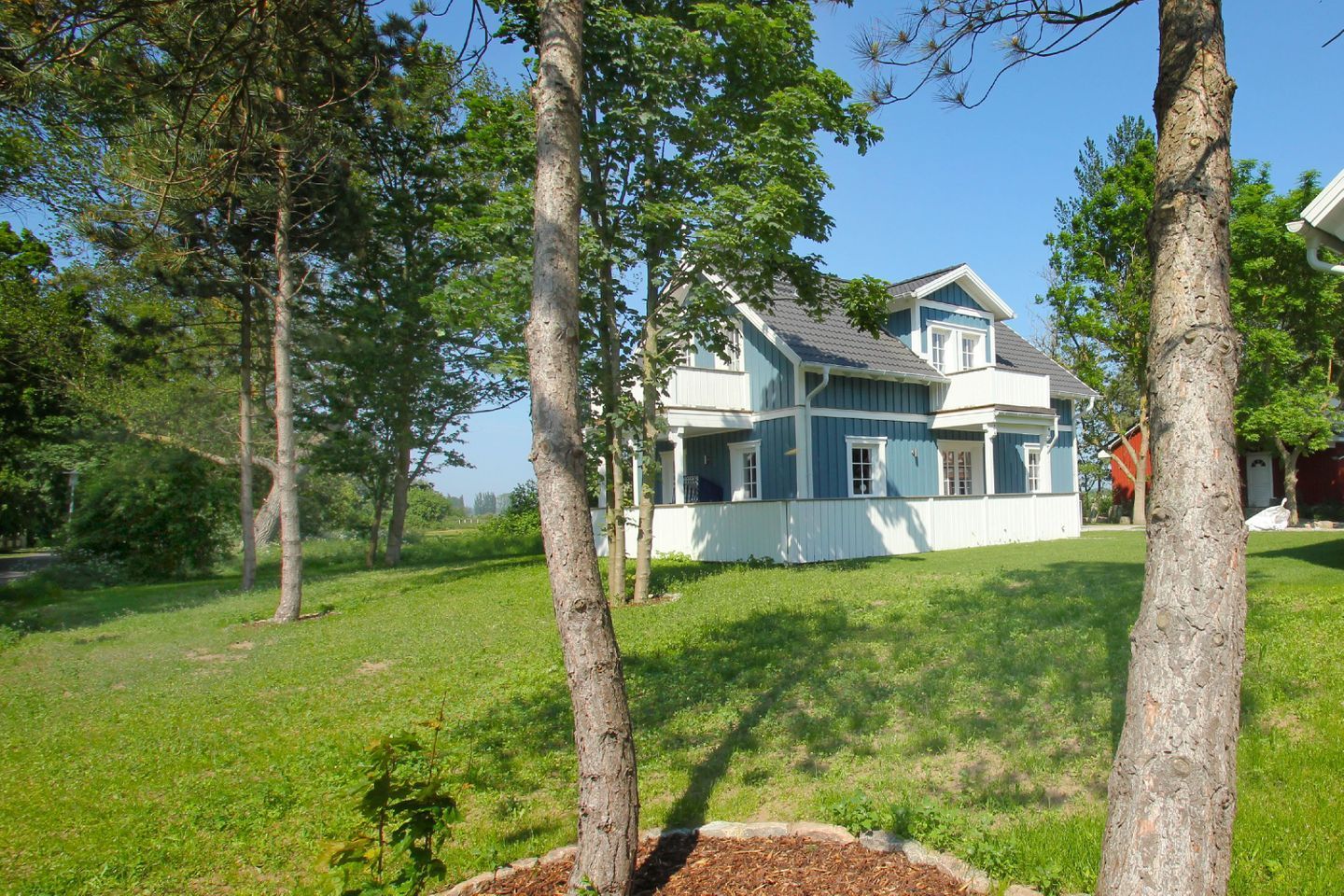A two-story house with a large front porch and a well-maintained lawn.